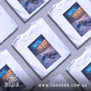 Футболка міська жесть, біла, зображена на манекені, фон світло-сірий, принт з зображенням людини, що лежить у снігу з лопатою, на фоні магазину з неоновим написом 'ЖЕСТЬ'.