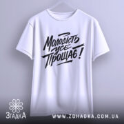 Футболка молодість усе прощає. Білий колір, зображена з фронтального ракурсу, фон світло-сірий. Принт чорного кольору з написом "Молодість усе прощає!" у стилі рукописного шрифту.