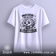 Футболка мозок це круто. Біла футболка з коротким рукавом, зображена з фронтального ракурсу. На футболці чорний принт з веселим мозком та написом 'МОЗОК - ЦЕ КРУТО'. Фон світлий, з плавними градієнтами.