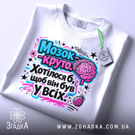 Футболка мозок це круто. Біла футболка, складена на поверхні, з яскравим принтом, що включає мозок та текст. Принт виконаний у рожевих і блакитних тонах. На футболці є етикетка.