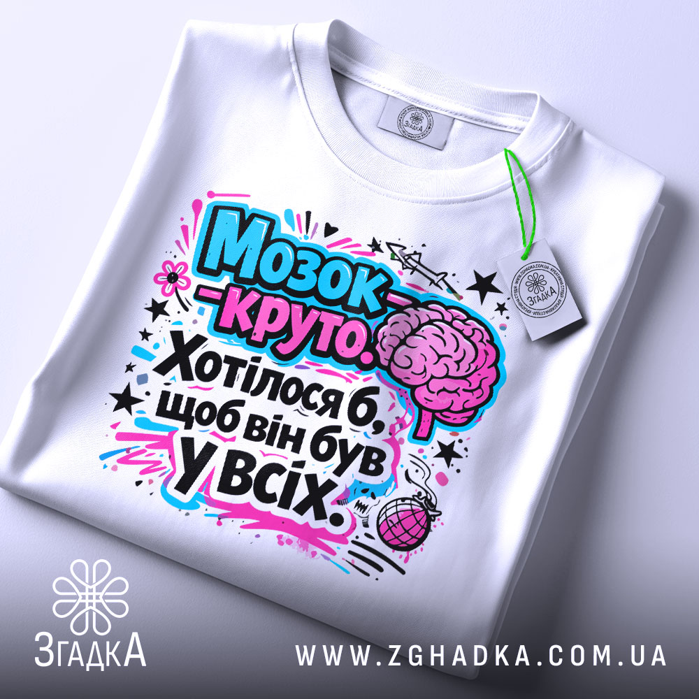 Футболка мозок це круто. Біла футболка, складена на поверхні, з яскравим принтом, що включає мозок та текст. Принт виконаний у рожевих і блакитних тонах. На футболці є етикетка.
