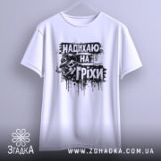 Футболка надихаю на гріхи, біла, підвішена на вішалці, фон світло-сірий, принт чорного кольору з черепом у капелюсі, виглядає стильно і привертає увагу.