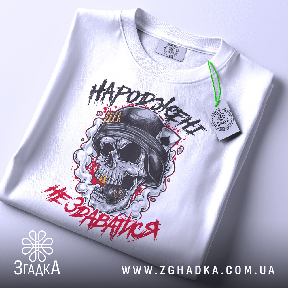 Футболка народжені не здаватися, білого кольору, зображена зверху, на ній видно етикетку, фон світло-сірий, принт з черепом у військовій касці, оточений димом та червоними акцентами.