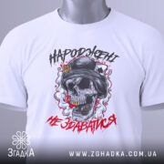 Футболка народжені не здаватися, білого кольору, зображена зверху, на ній видно етикетку, фон світло-сірий, принт з черепом у військовій касці, оточений димом та червоними акцентами.