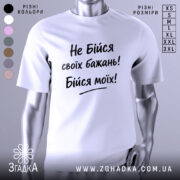 Футболка не бійся бажань. Біла футболка з коротким рукавом, зображена з правого ракурсу на манекені, фон світло-сірий, принт чорного кольору з текстом "Не Бійся своїх бажань! Бійся моїх!".