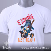 Футболка не зупиняйся, біла, зображена зверху, на ній видно етикетку, фон світло-сірий, принт з малюнком ведмедя на триколісному велосипеді з червоним текстом 'НЕ ЗУПИНЯЙСЯ' та 'ГАЗ У ПІДЛОГУ'.