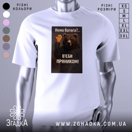 Футболка нема батога. Біла футболка з коротким рукавом, зображена з фронтального ракурсу на манекені. На фоні світло-сірий градієнт. Принт з ведмедем, який тримає пряник у формі черепа, з текстом на українській мові.