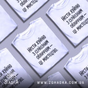 Футболка нести хуйню, білого кольору, з серйозним обличчям на манекені, фон світлий, принт чорного кольору з текстом: 'Нести хуйню з серйозним обличчям – це мистецтво.'