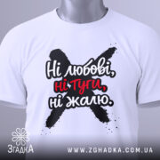 Футболка ні любові, біла, зображена зверху, складена на поверхні, фон світлий, принт чорного кольору з червоними акцентами, текст "Ні любові, ні туги, ні жалю" чітко видимий, на футболці є етикетка з зеленим шнурком.