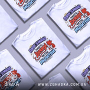 Футболка поруч зі мною, білого кольору, з принтом на грудях, зображує червоного диявола, який читає молитви, фон світло-сірий, ракурс з правого боку.