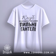Футболка пильні гантелі, біла, зображена на вішалці, фон світло-сірий, принт чорного кольору з текстом 'Клуб анонімних менеджерів' та 'Пильні гантелі'.