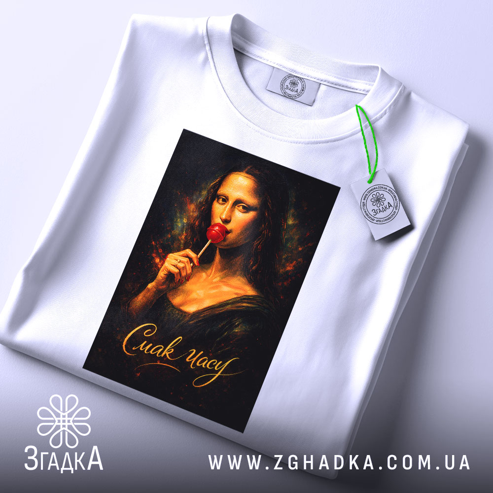 Футболка смак часу. Біла футболка, складена на поверхні, з принтом Мони Лізи, яка тримає червоний льодяник, фон темний, текст 'Смак часу' золотистий, на футболці є етикетка з зеленим шнурком.