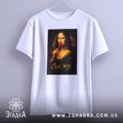 Футболка смак часу. Біла футболка, висяча на вішалці, з принтом Мони Лізи, яка тримає червоний льодяник, фон світлий, текст 'Смак часу' золотистий, рукава вільні.