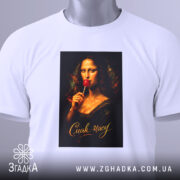 Футболка смак часу. Біла футболка, складена на поверхні, з принтом Мони Лізи, яка тримає червоний льодяник, фон темний, текст 'Смак часу' золотистий, на футболці є етикетка з зеленим шнурком.