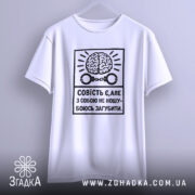 Футболка совість є білого кольору, зображена на манекені, фон світло-сірий, принт чорного кольору з малюнком мозку та наручниками, текст українською мовою, рукава короткі.