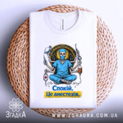 Футболка спокій це анестезія, біла, зображена зверху на плетеній основі, фон нейтральний, принт з черепом у медичному одязі, що сидить у позі лотоса, з медичними інструментами, текст на футболці жовтого кольору.