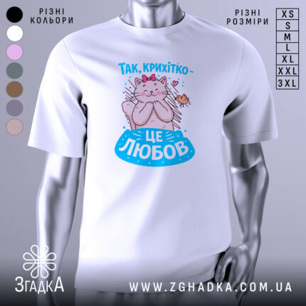 Футболка це любов. Біла футболка з принтом, на якому зображена кішка з рожевою стрічкою на голові, що обіймає пташку. Принт виконаний у яскравих кольорах, фон нейтральний, а футболка представлена на манекені.