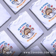 Футболка це не втома. Біла футболка з принтом, зображення їжачка, що сидить у чашці з кавою, на фоні з годинниками та значками, ракурс спереду, гладка текстура тканини.