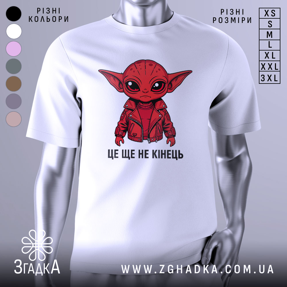 Футболка це ще не кінець. Біла футболка з принтом червоного персонажа з великими вухами, що одягнений у червону куртку, зображена з фронтального ракурсу на нейтральному фоні. Принт містить текст "ЦЕ ЩЕ НЕ КІНЕЦЬ".