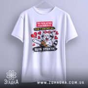 Футболка ти мені подобаєшся. Біла футболка на вішалці, з принтом кота з бензопилою, знята з легким нахилом, фон однотонний, світлий.