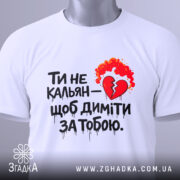 Футболка ти не кальян. Біла футболка, зображена зверху, на плоскій поверхні. На футболці великий принт з червоним серцем та вогнем. На комірці видно етикетку з логотипом бренду.