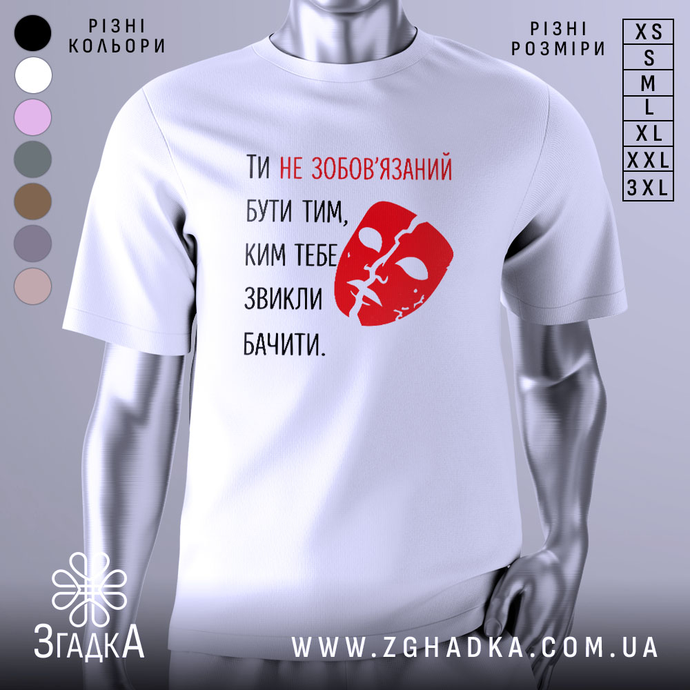 Футболка ти не зобов’язаний білого кольору, з принтом червоного кольору у вигляді маски та текстом, розташована на манекені, фон нейтральний, з легким градієнтом.