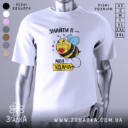 Футболка удача поруч, біла футболка на манекені, з принтом жовтої бджоли з блакитними крилами, що тримає червоне серце, на фоні світло-сірого кольору.