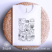 Футболка Україна мій світ, біла, складена на плетеній основі, фон натуральний, принт чорного кольору з малюнками та текстами, включаючи тризуб і сонце.