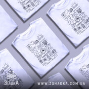 Футболка Україна мій світ, біла, зображена на манекені, фон градієнтний сірий, принт чорного кольору з різними символами та написами, включаючи тризуб і сонце.