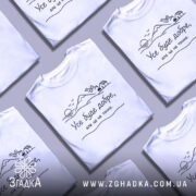 Футболка усе буде добре, на білому фоні, зображена з фронтального ракурсу, на грудях принт з пейзажем, що містить гори, сонце та будинок, текст чорного кольору.