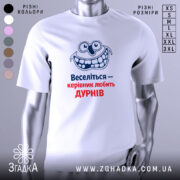 Футболка веселий керівник. Біла футболка, зображена з фронтального ракурсу на манекені, фон світло-сірий. Принт з усміхненим персонажем та текстом "Веселіться — керівник любить ДУРНІВ" у синьому та червоному кольорах.