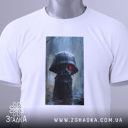 Футболка володар тіні, білого кольору, зображена на столі, ракурс зверху, фон світлий, принт з персонажем у чорному капюшоні з червоними очима, на футболці є етикетка з зеленим шнурком.