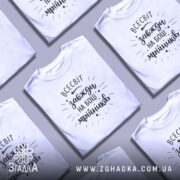 Футболка всесвіт на боці, біла, зображена на манекені з правого ракурсу, фон світло-сірий, принт чорний з написом 'всесвіт завжди на боці мрійників' та декоративними зірочками.