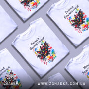 Футболка винна бешкетниця, білого кольору, зображена на манекені з блискучою поверхнею, фон нейтральний, принт з веселим чорним котом з червоним вином та кольоровими плямами.