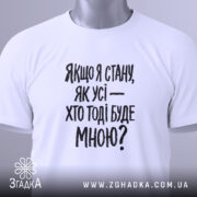 Футболка з філософським написом, білого кольору, складена на поверхні, фон світло-сірий, принт чорного кольору з текстом: 'Якщо я стану, як усі — хто тоді буде мною?', на комірці видно етикетку.