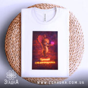 Футболка з фразою любові, біла, зображена зверху, фон світлий, принт з мишеням, що тримає сердечко, текст під малюнком: 'Тримай і не впендривайся', футболка лежить на плетеній основі.