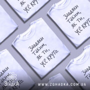 Футболка завдяки таким людям, білого кольору, зображена на манекені, фон світло-сірий, принт чорного кольору з текстом 'Завдяки таким, як ти, усе круто.'