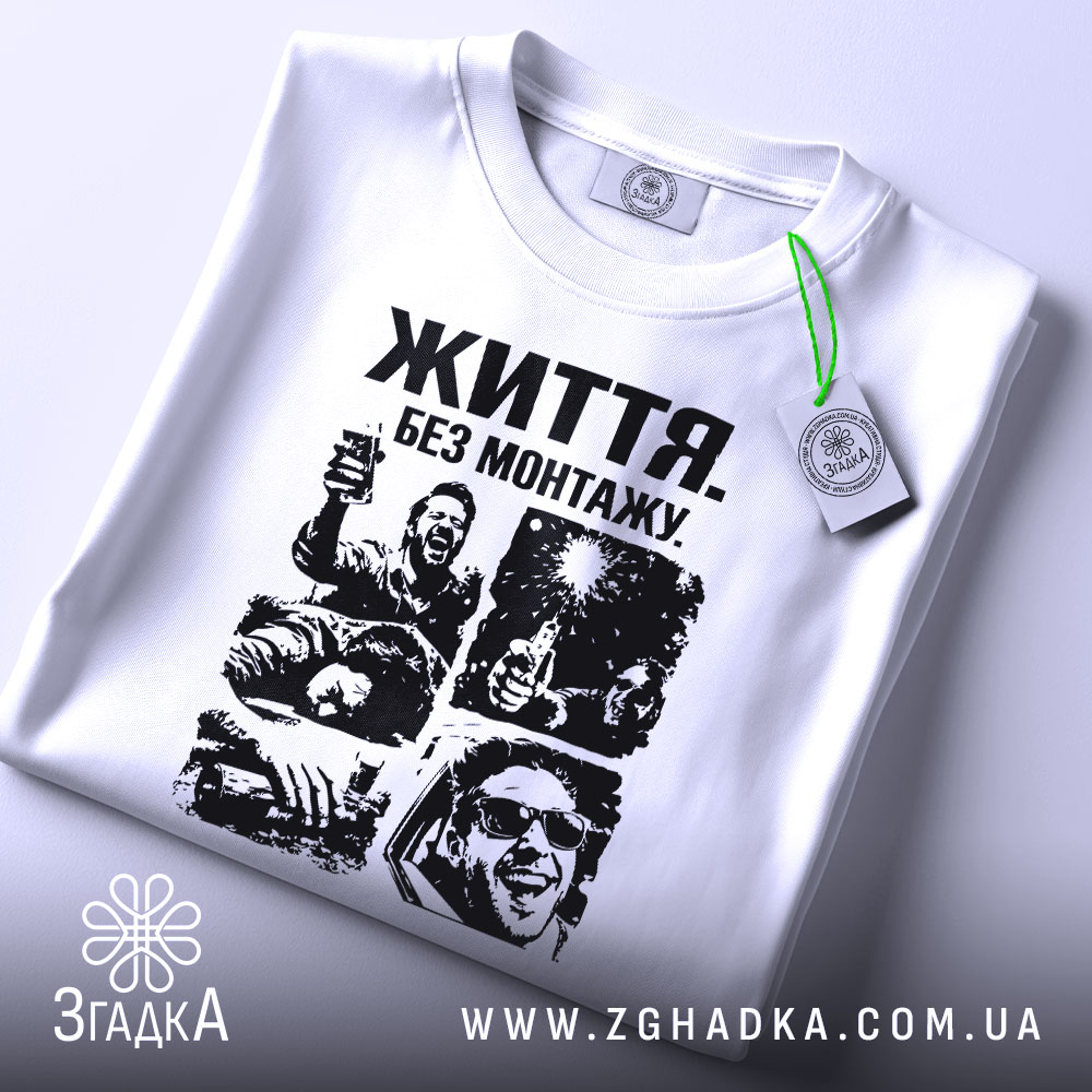 Футболка життя без монтажу. Біла футболка, складена на столі, з чорним принтом, що містить чотири сцени. На футболці видно етикетку з зеленим шнурком. Фон світло-сірий, що створює контраст з футболкою.