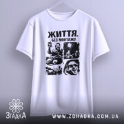 Футболка життя без монтажу. Біла футболка, підвішена на вішалці, з чорним принтом, що зображує емоційні сцени. Фон світло-сірий, що акцентує увагу на дизайні футболки.