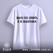 Футболка життєвий тиск, біла, підвішена на вішалці, фон світло-сірий, принт чорного кольору з текстом 'Життя тебе душить. А ти збуджуєшся.'
