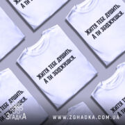 Футболка життєвий тиск, біла, зображена на манекені, фон світло-сірий, принт чорного кольору з текстом 'Життя тебе душить. А ти збуджуєшся.'