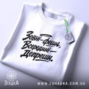 Футболка зовні фешн, біла, складена на поверхні, з видимим етикеткою, фон світло-сірий, принт чорний з текстом 'Зовні-фешн, Всередині—Депрешн.'