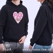 Худі з написом Fuck Love, чорного кольору, з капюшоном, на фоні світло-сірого кольору, з принтом у формі серця, де напис виконаний у рожевих тонах, з кишенею-«кенгуру», на моделі, що стоїть в профіль, з манжетами та поясом з еластичної тканини.