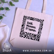 Шопер хліб молоко п*здець — кілька складених шоперів, композиція на столі.