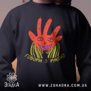 Світшот Говори з рукою, чорного кольору, зображений на дитині, фон розмитий, принт з червоною рукою та усміхненим обличчям, кругла горловина, манжети на рукавах, трикотажна резинка на поясі, фактура м'яка та комфортна.