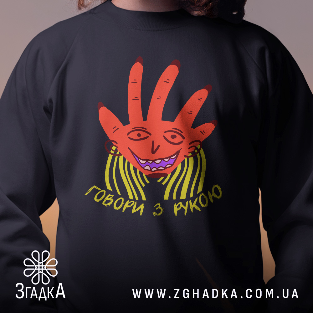 Світшот Говори з рукою, чорного кольору, зображений на дитині, фон розмитий, принт з червоною рукою та усміхненим обличчям, кругла горловина, манжети на рукавах, трикотажна резинка на поясі, фактура м'яка та комфортна.