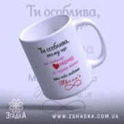 Чашка для коханої дружини, біла, з блискучою поверхнею, з написом чорного та рожевого кольорів, з сердечком, ручка з класичним дизайном, край рівний, нахилена вбік.