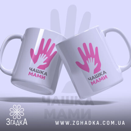 Чашка для мами, дві білих чашки, з ракурсом спереду, на фоні світло-фіолетового кольору, з принтом у вигляді двох рук, напис "ЧАШКА МАМИ" чорним шрифтом, ручки круглі, краї рівні, глянцеві.