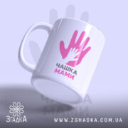 Чашка для мами, біла, з ракурсом зліва, на фоні світло-фіолетового кольору, з принтом у вигляді двох рук, одна з яких менша, напис "ЧАШКА МАМИ" чорним шрифтом, ручка кругла, край рівний, глянцевий.