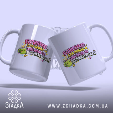 Чашка для Великих Ідей. Дві чашки білого кольору, зображені під кутом, на фоні з легким градієнтом. Принт яскравий, з текстом і малюнком чашки з обличчям. Ручки круглої форми, краї рівні, глянцеві.